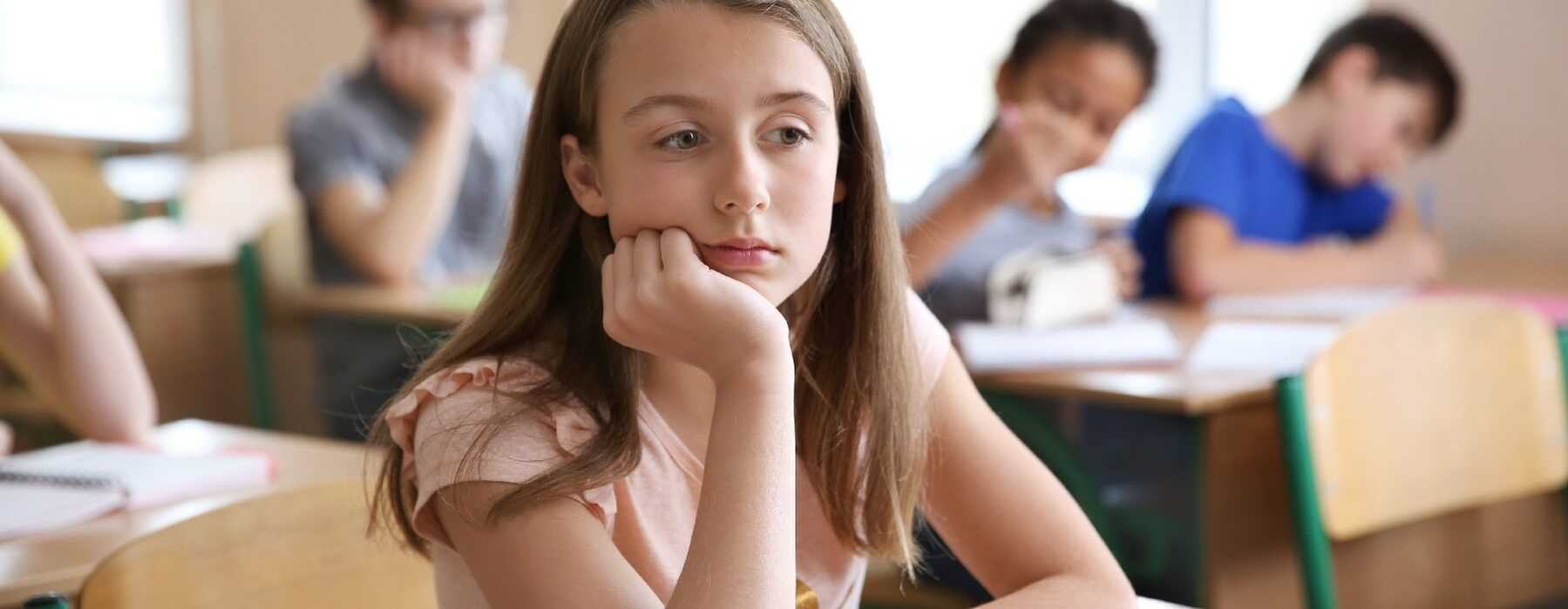 Girl looking uncertain while sitting at school desk